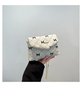 Detail of corduroy texture and black bow pattern on small chain shoulder bag