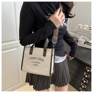 Détail du grand sac cabas en toile avec garniture en cuir marron et large sangle sur modèle