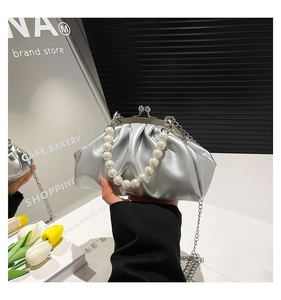 Close-up of metallic silver pleated cloud bag with pearl handle and metal chain detail