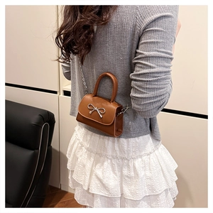 Vue détaillée d'un mini sac en cuir marron avec boucle nœud argentée et bandoulière