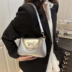 Silver metallic baguette shoulder bag with gold bow emblem and chunky chain strap