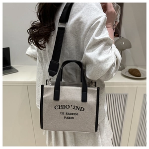 Detail of printed canvas tote bag with black leather handles and adjustable wide strap