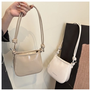 Detail of minimalist saddle bags in beige and cream white with knotted strap design