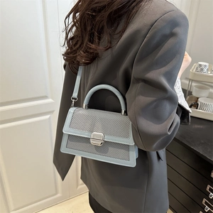 Borsa a mano celeste con trama intrecciata e manico indossata da una modella