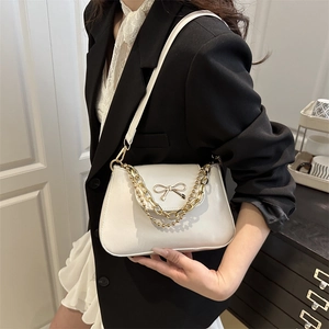 Elegant white leather baguette bag with metal bow detail and gold chain shoulder strap