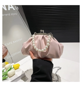 Detail of light pink cloud bag featuring pleated leather and elegant pearl handle