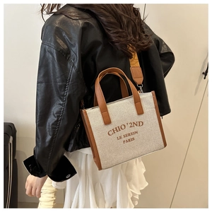 Detail of canvas tote bag with brown leather trim and stylish wide shoulder strap