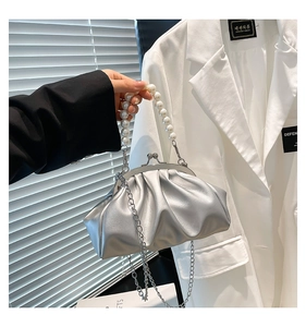 Detailed shot of silver pleated cloud bag featuring large pearl handle and metal clasp