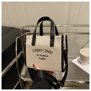 Detail of printed canvas tote bag with black leather handles and shoulder strap