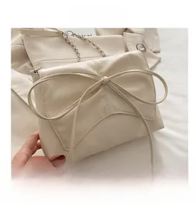 Détail du sac à bandoulière crème avec grand nœud décoratif et chaîne en argent