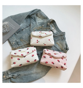 Detail of three corduroy envelope bags with cherry and strawberry prints on denim background