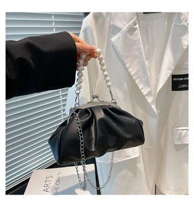 Detail of the pearl handle and silver chain on a black pleated cloud bag for women