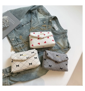 Detailed view of three corduroy envelope bags with heart and bow patterns on denim