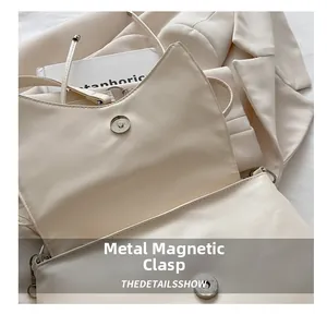 Détail de la fermeture magnétique en métal sur un sac à main minimaliste en cuir beige