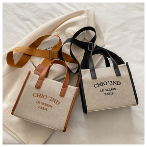 Detail view of two minimalist canvas tote bags with leather trim and wide crossbody straps