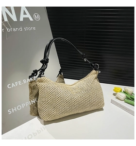 Detail of beige straw woven tote bag featuring black knot shoulder straps and fine texture