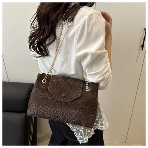 Detail of a brown snakeskin shoulder bag featuring golden chain strap and textured leather