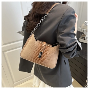 Detail of tan crocodile-embossed leather underarm bag with a silver metallic clasp