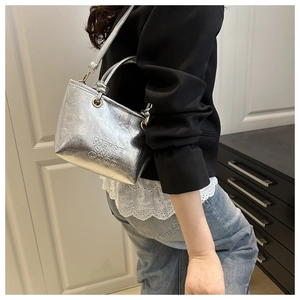 Detailed close-up of metallic silver bucket bag with embossed logo and wrinkled texture