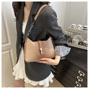 Detail of brown crocodile pattern shoulder bag with metal twist lock and silver chain strap