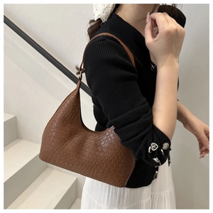 Detail of dark brown woven texture and adjustable metal buckle on a retro shoulder bag