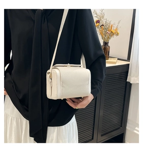 Gros plan d'un sac bandoulière blanc cassé en cuir grainé avec détails dorés