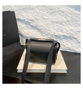 Détail du sac bandoulière en cuir grainé noir avec fermoir rotatif doré élégant