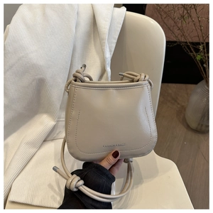 Detail of knot shoulder strap and metal hardware on beige minimalist crossbody bag
