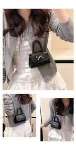 Détail du mini sac bandoulière noir avec boucle nœud argenté et bandoulière en chaîne