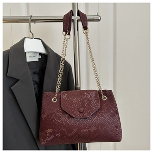 Detail shot of vintage burgundy snake-pattern bag with elegant gold chain shoulder strap