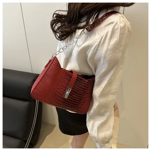 Detailed view of red crocodile-patterned shoulder bag with silver clasp and chain strap