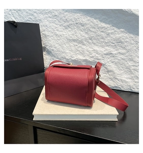 Détail du sac en cuir rouge à motif litchi avec fermoir doré élégant et texture naturelle
