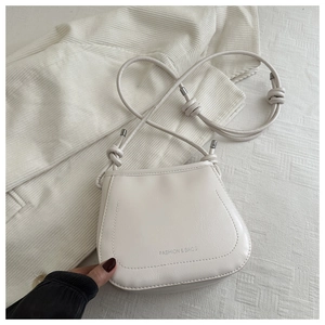 Detail of cream leather crossbody bag with FASHION & BAGS embossed text and knot strap