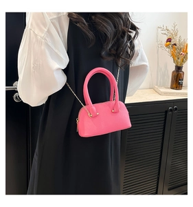 Close-up of bright pink shell bag featuring lychee texture and gold chain strap detail