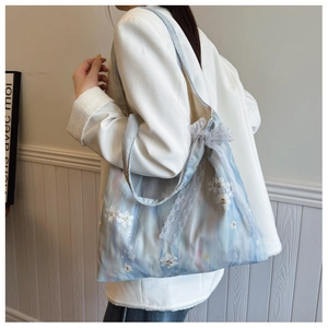 Detail of light blue floral tote bag with white lace trim and daisy embroidery