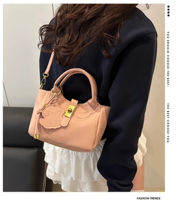 Detail der rosa Handtasche mit Litschi-Leder, goldenem Drehverschluss und Hundeanhänger