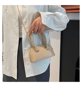 Close-up of litchi grain texture on beige shell bag with elegant gold chain strap