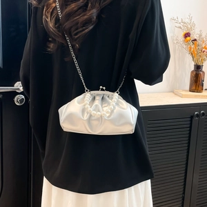 Silver pleated cloud bag with pearl handle and metal chain shown on a model