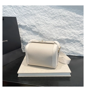 Détail du sac bandoulière crème avec texture grainée et fermoir rotatif doré en métal