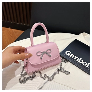 Gros plan du sac bandoulière rose avec nœud argenté et chaîne en métal élégante