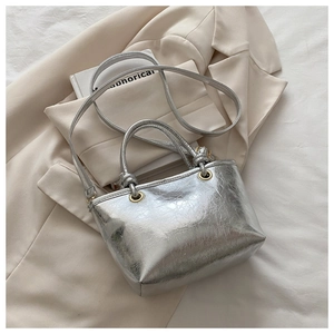 Detail of silver metallic textured bucket bag with cylindrical handle and shoulder strap