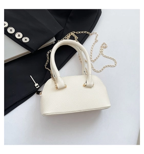 Close-up of white lychee textured shell bag with gold chain and round top handle