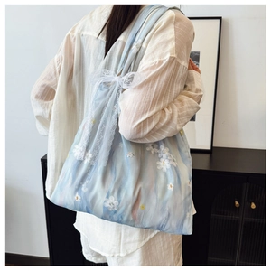Detailed close-up of light blue tote bag with white lace flowers and side ribbon bow