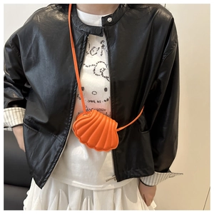 Detail of an orange shell-shaped mini crossbody bag with textured matte PU leather