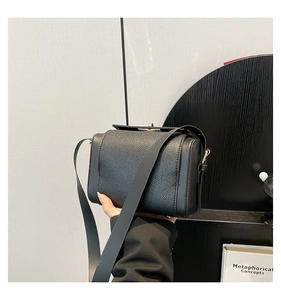 Gros plan d'un sac bandoulière en cuir noir avec fermoir métallique doré