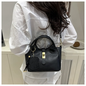 Vue arrière d'un sac seau noir en cuir grainé avec un pendentif d'ours en peluche