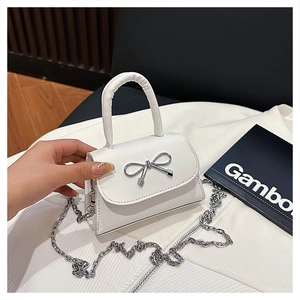 Détail du mini sac blanc en cuir avec nœud argenté et bandoulière en chaîne