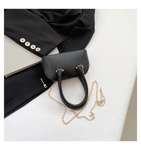 Detailed view of black litchi pattern leather shell bag with golden chain strap