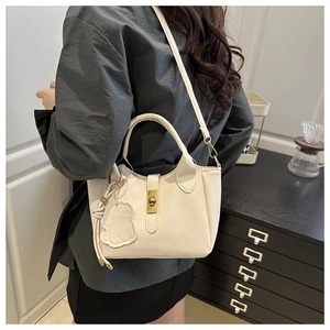 Detail of cream leather bucket bag with gold twist lock and cute puppy charm accessory