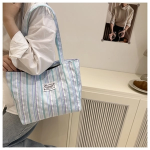 Detailed texture of a striped canvas tote bag with a fashion logo patch for daily commute